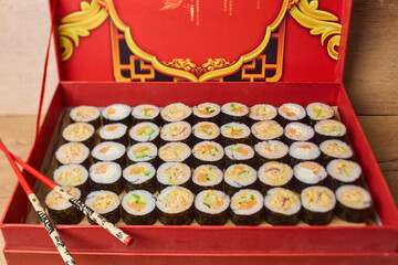 Sushi maki rolls in red Chinese gift box with chopsticks traditional packaging © smslov