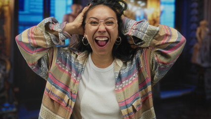 Woman hands on head laughing with mouth open in museum building, wearing glasses, hoop earrings and patterned shirt  joy discovery. © Krakenimages.com