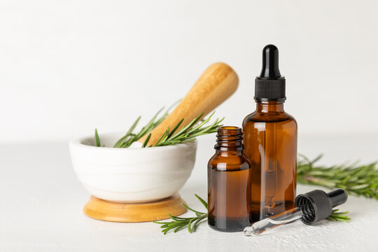 Rosemary essential oil on a textured background. Rosemary essential oil with fresh leaves nearby. Green rosemary sprig. Natural medicine, organic hair product, skin care, spa therapy. Beauty concept. 