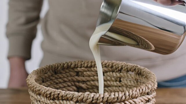 Pouring milk from a metal pitcher into a woven basket concept