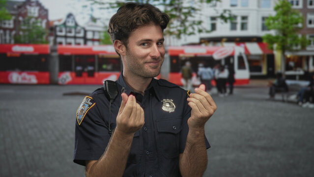 Man policeman pinches fingers with both hands on street, navy uniform with visible badge and radio microphone, smiling while hands are prominent; playful greeting.