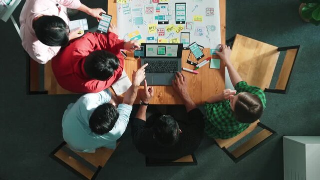 Top view of project manager using laptop working on Ux Ui design for mobile phone interface while marketing team designing software program by using brainstorming mind map. Time lapse. Convocation.