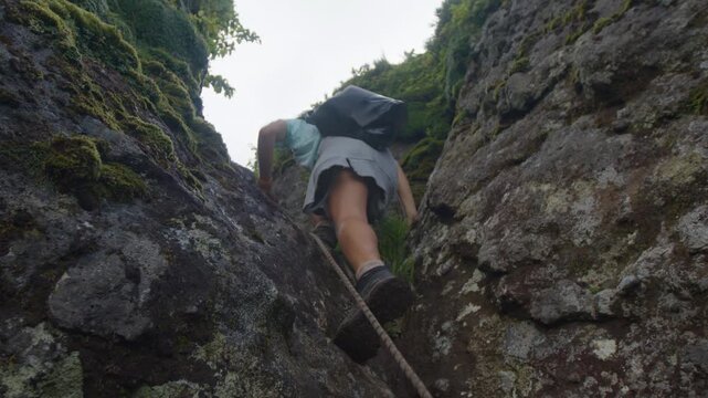 Woman hiker climbs on the tricky trail in the wild volcanic area on Kunashir Island. Russia
