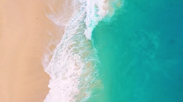 Aerial drone footage of massive turquoise waves crashing on a sandy tropical beach. Top view of powerful ocean surf and blue sea water. Concept of nature power, travel destination and summer.