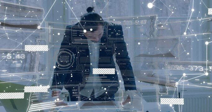 Vertical video: Entering man leaning at studio desk, flattening plans, reviewing with HUD in blazer