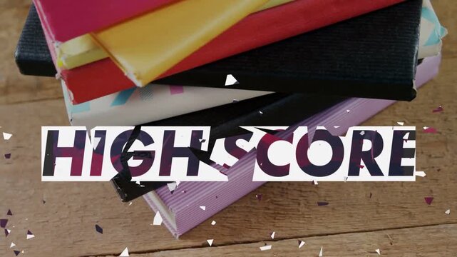 Animating HIGH SCORE overlay dissolving into shards above notebook stack on table, revealing covers