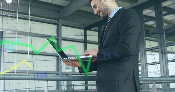 Vertical video: Man on mezzanine holding laptop typing, causing finance graphs moving across laptop