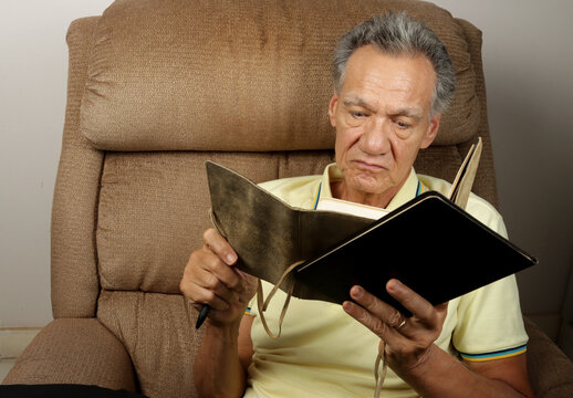 Senior Man seated in a Recliner writing in his Journal