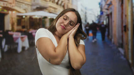 Woman wearing glasses and white t shirt smiling while touching hair with hands behind head at...