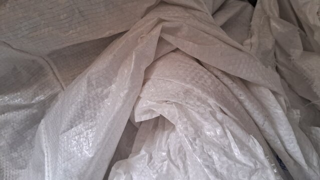Abstract background of intricately folded white woven plastic tarp material with geometric patterns