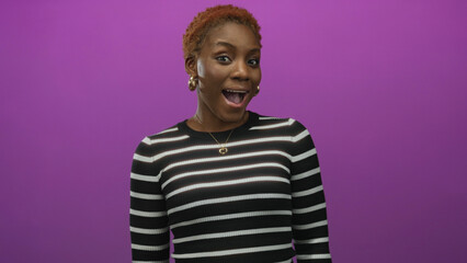 Woman in black and white striped top wearing gold hoop earrings and heart necklace with open mouth in studio  surprise. © Krakenimages.com