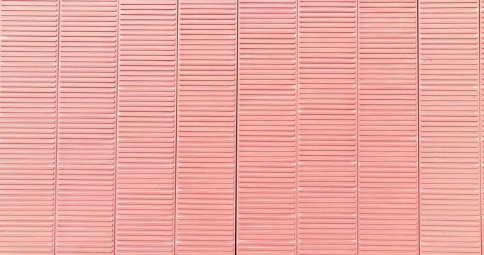 Pink corrugated metal surface of shipping container rooftop showing parallel lines and industrial texture for background design.