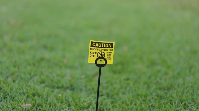 Close-Up of Pesticide Caution Warning Sign being staked into a green Lawn