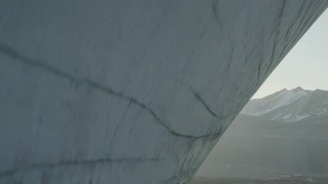 Concrete brutalist building exterior featuring angular geometric shapes and a minimalist design, creating a strong contrast with the natural background of snow capped mountains