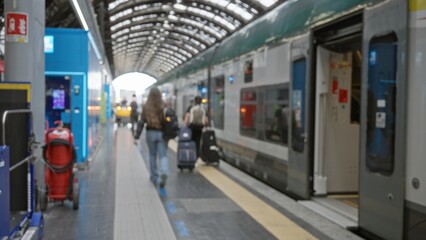Fototapeta premium Train platform defocused background with soft bokeh, blurred luggage and open carriage under arched roof; background copyspace backplate calm.