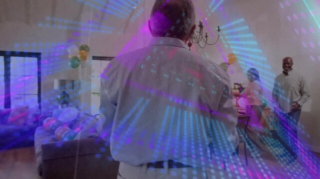 Man picking up glasses at counter, starting party table setup while animated lights overlaying room