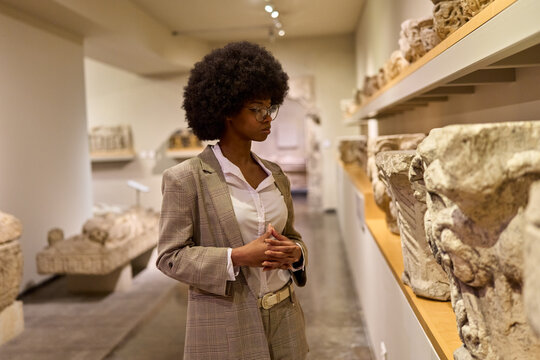Woman wearing glasses and looking at exhibition. Concept of Museum Day.