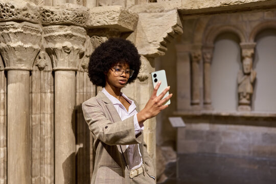 Woman wearing glasses and looking at exhibition. Concept of Museum Day.