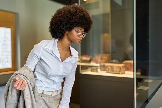 Woman wearing glasses and looking at exhibition. Concept of Museum Day.