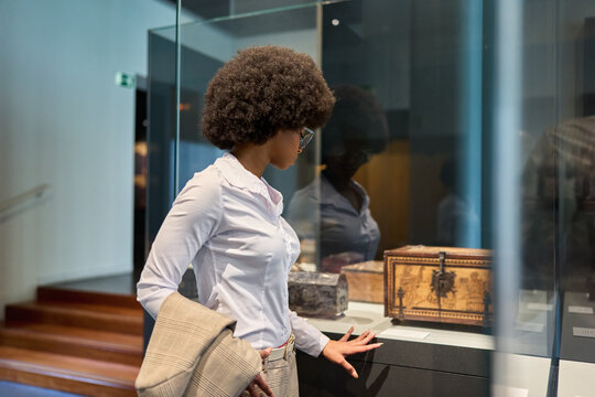 Woman wearing glasses and looking at exhibition. Concept of Museum Day.