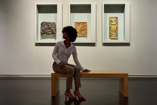 Woman wearing glasses and looking at exhibition. Concept of Museum Day.