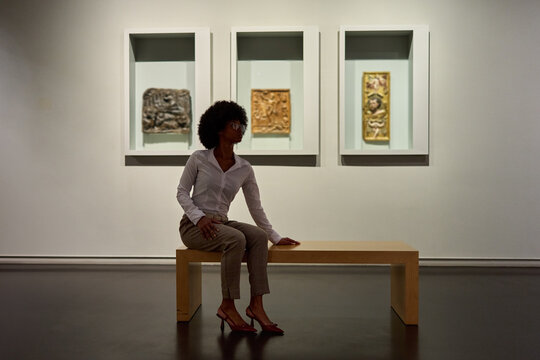 Woman wearing glasses and looking at exhibition. Concept of Museum Day.