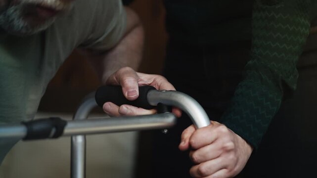 Close-up of caring woman helping senior husband to move with a walker, recovery