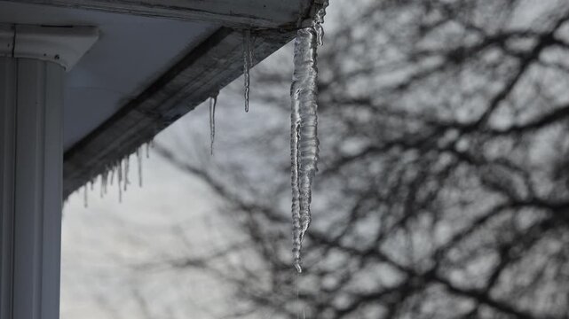 Gla&ccedil;ons suspendus au toit d'une maison. Paysage d'hiver