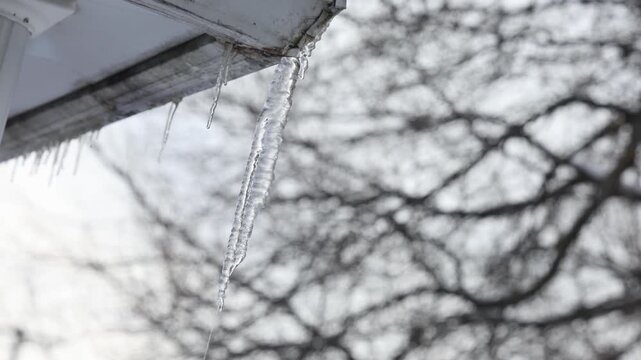 Gla&ccedil;ons suspendus au toit d'une maison. Paysage d'hiver
