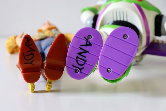 Salvador, Brazil - March 20, 2026: Close-up of the feet of Woody and Buzz Lightyear action figures with 'Andy' written on the sole. Toy Story movie. 