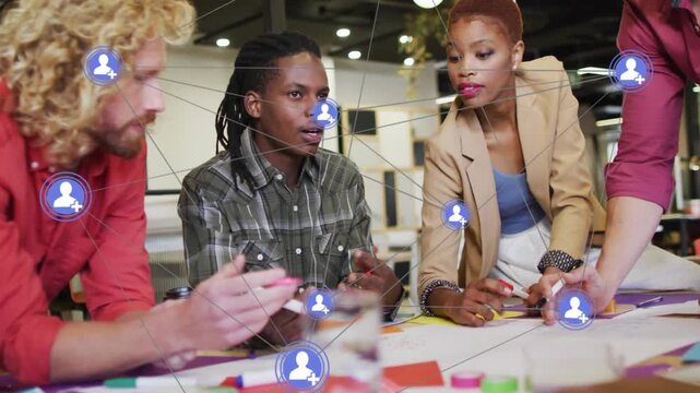 Team of four leaning in while lead speaker starting talk, network icons appearing and mapping ideas