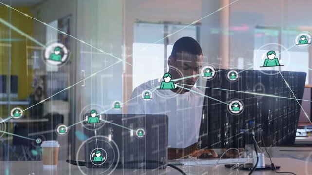 Typing mid-adult man in white tee at open office monitoring screens while network overlay expanding