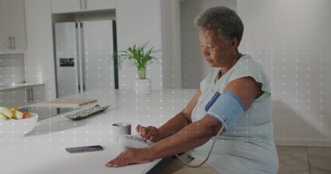 Vertical video: Tapping monitor senior in light top checking BP at kitchen, cuff, ECG, copy space