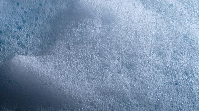 Close up of dense soap foam bubbles creating abstract texture background for cleaning hygiene and washing concept. Foamy soap bubbles rotates