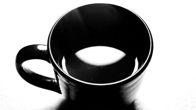 Black coffee mug viewed from above with rising steam and white background, minimalistic, monochrome