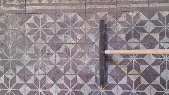 Floor squeegee tool beginning sweeping motion across antique geometric patterned tile footage