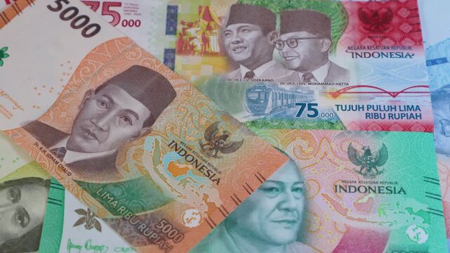A rotating close-up of Indonesian Rupiah banknotes, featuring various denominations like 5,000, 20,000, and 75,000. The video highlights colorful designs and portraits of Indonesia's national heroes.