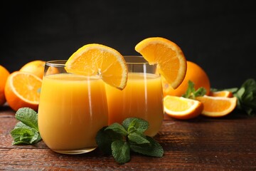 Citrus juice in glasses, fresh oranges and mint leaves on wooden table, closeup © New Africa