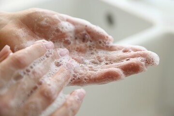 Fototapeta premium Woman washing hands with soap against blurred background, closeup