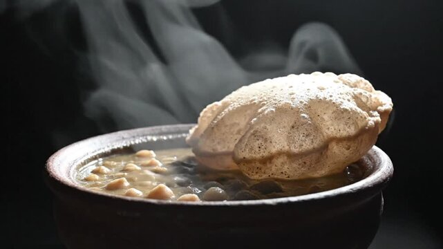 Steaming bowl of Indian chana masala with puffed puri bread, traditional vegetarian cuisine