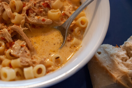 Close-up of a delicious and comforting bowl of creamy shredded chicken and ditalini pasta in a rich orange sauce, perfectly paired with fresh crusty bread, ideal for a hearty meal.
