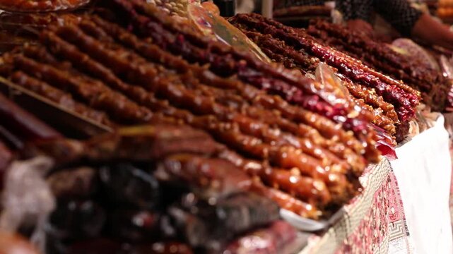 A close-up shot showing rows of colourful Churchkhela, a traditional Caucasian sweet made of nuts and grape juice, beautifully displayed for sale at a local food market stall.