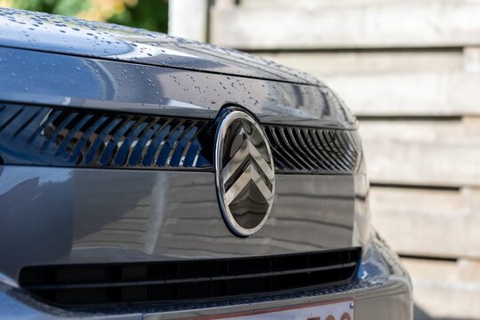 Brecht Belgium - 10 October 2025: Close-up of a Citro&euml;n car emblem on a wet, reflective front grille, emphasizing chrome detail, texture and raindrops.