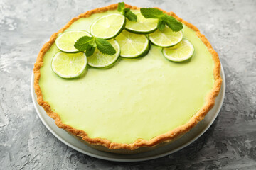 Tasty lime pie with fruit slices and mint leaves on grey textured table, closeup © New Africa