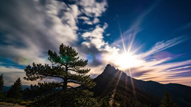 Epic scenic mountain landscape with sun rays breaking through fast moving clouds at sunset
