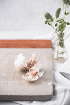 Head of Garlic Open on Cutting Board with Green Herbs and Knife Beside