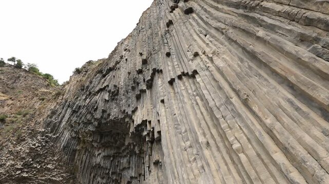 A breathtaking view of a massive cliff face composed of unique, vertical hexagonal basalt rock columns. This stunning natural geological formation looks like a giant, ancient stone organ.