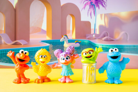Utica, NY - Jan 1, 2026: Five Sesame Street character figurines&mdash;Elmo, Big Bird, Abby Cadabby, Oscar the Grouch, and Cookie Monster&mdash;in a pastel poolside setting with stylized props and soft colors