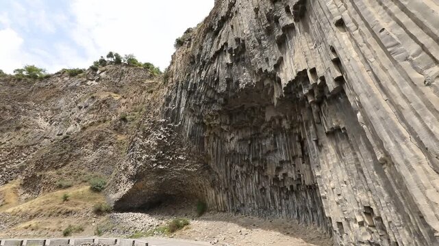 A breathtaking view of a massive cliff face composed of unique, vertical hexagonal basalt rock columns. This stunning natural geological formation looks like a giant, ancient stone organ.