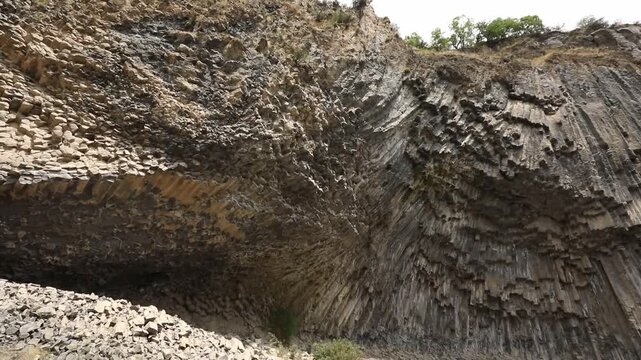 A breathtaking view of a massive cliff face composed of unique, vertical hexagonal basalt rock columns. This stunning natural geological formation looks like a giant, ancient stone organ.
